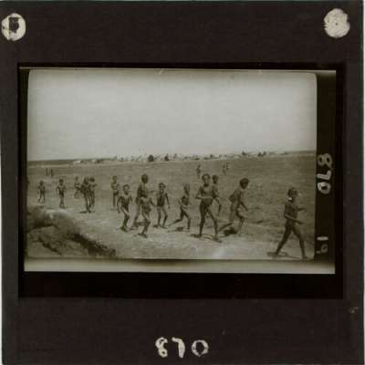 Lantern Slide: Group of boys running with camp in background
