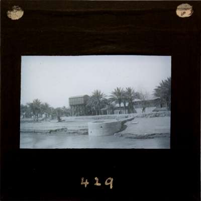 Lantern Slide: River bank with water tank and buildings